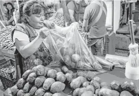  ?? Nick Wagner / Associated Press ?? Avocados, which have been commanding higher prices, are bagged up in Mexico City. The trees grow at about the same altitude as pine and fir trees in Michoacan.