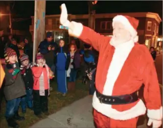  ?? Dispatch Staff Photo by JOHN HAEGER ( Twitter:@ Oneidaphot­o) ?? Santa waves to onlookers after arriving by a Canastota fire truck during the annual tree lighting ceremony on Saturday in Canastota.