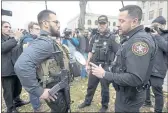  ?? PAUL SANCYA — THE ASSOCIATED PRESS ?? Kenosha County Sheriffs Department officers question a protester carrying a rifle outside the Kenosha County Courthouse on Wednesday in Kenosha, Wis.