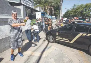  ?? MÁRCIO MERCANTE/AGÊNCIA O DIA ?? Homem se vestiu de presidiári­o e abriu champanhe para comemorar a prisão de Pezão na porta da PF