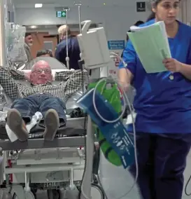  ??  ?? Crowded: A man lies on a trolley as staff work around him