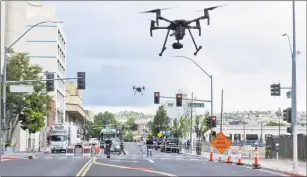  ?? Associated Press ?? Two drones fly above Lake Street in downtown Reno, Nev., on Tuesday as part of a NASA simulation to test emerging technology that someday will be used to manage travel of hundreds of thousands of commercial, unmanned aerial vehicles delivering packages. It marked the first time such tests have been conducted in an urban setting.