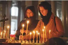  ?? AP ?? Women light candles in memory of victims of the shooting, in a church in St.Petersburg. Russia said that it has deployed officers and riot police to all schools and colleges in Kerch.
