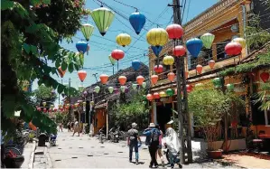  ??  ?? Passeio. Luminárias coloridas (à esq.) estão à venda em An Hoi; casas amarelas da área tombada (no alto); à direita, Templo chinês Phuc Kien