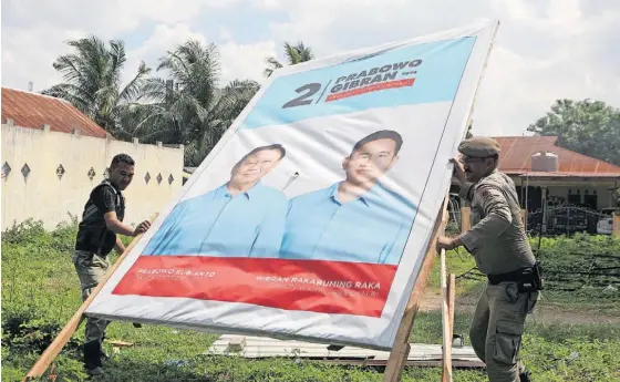  ?? ?? Três dias antes do escrutínio, a polícia retira da via pública toda a propaganda política, como este cartaz de Prabowo e de Gibran.