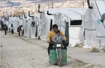  ?? Hussein Malla / Associated Press ?? A Syrian man and his son ride a motorcycle at a refugee camp in eastern Lebanon’s Bekaa Valley. The Syrian conflict has resulted in the largest displaceme­nt crisis since World War II.