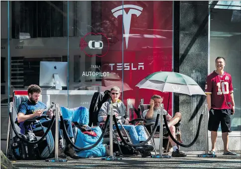  ?? ARLEN REDEKOP/PNG ?? Joseph Preece, left, and Grant Van Dyk, centre, head up the line of campers outside the Tesla showroom in downtown Vancouver waiting to put down deposits on the new Model 3, which will be unveiled Thursday night.