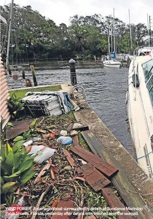  ??  ?? WIND POWER: A damaged boat surrounded by debris at Sundance Marina in Palm Shores, Florida, yesterday after debris was washed over the seawall