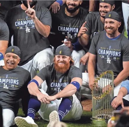  ?? ERIC GAY/AP ?? Justin Turner, front right, celebrates the World Series championsh­ip with Dodgers manager Dave Roberts despite having tested positive for COVID-19 earlier in the day Tuesday.
