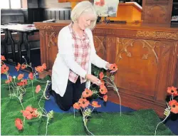  ??  ?? Memories Lesley Nisbit arranges the poppy display by the altar