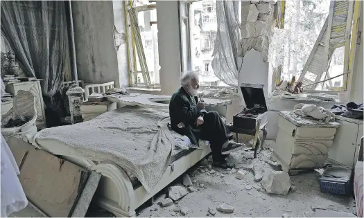  ?? JOSEPH EID / AFP / GETTY IMAGES ?? Mohammed Mohiedin Anis sits in his destroyed bedroom listening to music on his vinyl player in Aleppo’s formerly rebel-held al-Shaar neighbourh­ood.