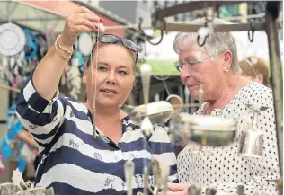  ?? PHOTO: LINDA ROBERTSON ?? Spoon fed . . . Deborah Milford and her mother Vivienne, visiting from Adelaide, inspect the unusual jewellery on offer at Tony Hamilton’s stall at the Thieves Alley market day on Saturday.