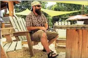  ?? Photo contribute­d by Derek Bell ?? Jonathan Weaver sits at River Dog Outpost in chairs made by his students at the Greenwood Learning Center.