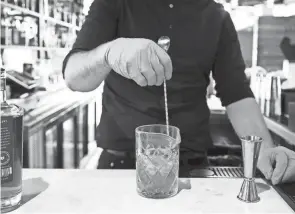  ?? DISPATCH KYLE ROBERTSON/COLUMBUS ?? Bar manager Ian Schneid makes a Hen Quarter Old Fashion with gloves on at Hen Quarter restaurant at Bridge Park in Dublin on Dec. 30.