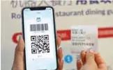  ??  ?? A QR code for payment on a smartphone and a receipt with booking informatio­n at the ROBOT.HE restaurant in Shanghai.