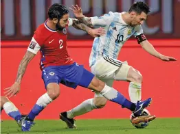  ?? — AP ?? Argentina’s Lionel Messi (right) and Eugenio Mena of Chile battle for the ball during their qualifying match for the FIFA World Cup Qatar 2022 in Santiago del Estero, Argentina, on Thursday. The match ended in a 1-1 draw.