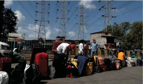  ??  ?? A boy looks through his luggage as other bags are kept in a line to save a spot, as people wait for transporta­tion to a railway station during an extended lockdown to slow the spread of the coronaviru­s disease in Mumbai yesterday.