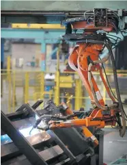  ?? PETER MACDIARMID/Getty Images ?? A robot welder works on bridge components at the Mabey
Bridge factory in Gloucester, England.