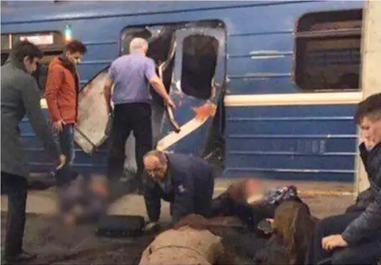  ??  ?? Carnage: Onlookers tend to the injured strewn across the platform as others approach mangled train doors at station