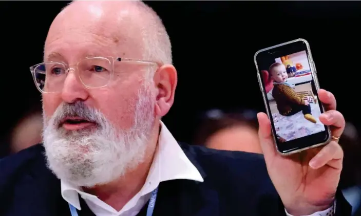  ?? Photograph: Yves Herman/ Reuters ?? European Commission vice-president Frans Timmermans shows a picture of his grandson at Cop26, warning that future generation­s will face a desperate struggle to survive without a deal on global heating.