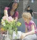  ?? AP PHOTO ?? Angel Sauls helps her stepdaught­er Coco Douglas arrange a sign and some painted rocks she made for a memorial in Portland, Ore.