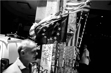  ??  ?? Greek national flags and a European Union flag flutter outside a shop in central Athens, Greece. Greece is expected to return to the bond markets in 2018, but having secured its third bailout programme Athens may test the waters by issuing a new bond...