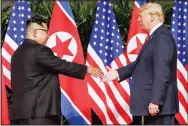  ?? (File Photo/AP/Evan Vucci) ?? U.S. President Donald Trump (right) reaches to shake hands with Kim on June 12, 2018, at the Capella resort on Sentosa Island in Singapore.