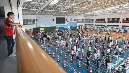  ?? — AFP ?? Taking precaution­s: Employees queueing to test for Covid-19 at the gym of a company in Wuhan in China’s central Hubei province.