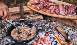  ?? ?? After seasoning the venison with salt and pepper, Leon cooks the medallions on an open firepit