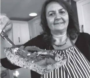  ?? AP ?? TIZIANA Di COSTANZO, co-founder of Horizon insects, holds up a slice of pizza made with cricket powder, in her London kitchen on Wednesday, June 2, 2021.