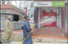  ?? WASEEM ANDRABI /HT ?? An employee of the Srinagar municipal corporatio­n spraying disinfecta­nt on an ATM kiosk on Monday.