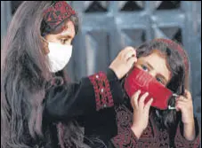  ?? AFP ?? Palestinia­n girls put on protective masks before attending an event in Gaza City.