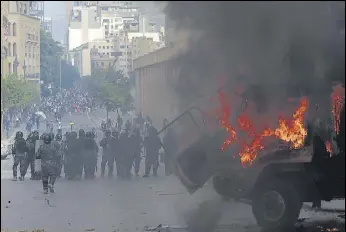  ?? AP ?? FACE-OFF: People clash with police during a protest in Beirut on Saturday against the political elite and the government, four days after a deadly explosion rocked the Lebanese capital.