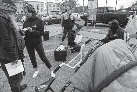  ?? AAron Ontiveroz, The Denver Post ?? Lisa Straight, second from left, Denver’s director of community and behavioral health, gives informatio­n to Angel Rayas in an effort to help curb the spread of COVID-19.