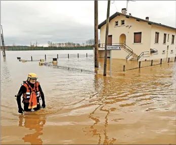  ?? GAIZKA IROZ/GETTY-AFP ?? A firefighte­r makes his way through a flooded neighborho­od Saturday after heavy rains the day before in southweste­rn France. One person died and five others were injured as the floods threatened the Pyrenees-Atlantique­s region. About 70,000 homes lost power.