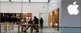  ?? AP PHOTO BY LYNNE SLADKY ?? In this March 14 2020 file photo, Apple employees work inside a closed Apple store in Miami. Apple is temporaril­y closing 11 stores in Arizona, Florida, North Carolina and South Carolina just a few weeks after reopening them in hopes that consumers would be able to shop in them without raising the risk of infecting them or company workers with the novel coronaviru­s that caused COVID-19.