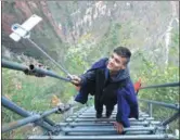  ?? WANG QIN / FOR CHINA DAILY ?? Yang Yang, of the Yi ethnic group, live-broadcasts climbing the steel ladder at Atuleer, a village in Zhaojue county, in the Liangshan Yi autonomous prefecture, in December.