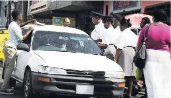  ?? FILE ?? Transport Authority inspectors check on a vehicle believed to be operating illegally as a taxi in the Corporate Area.