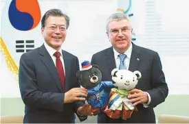  ?? Yonhap ?? President Moon Jae-in, left, presents the mascots of the 2018 PyeongChan­g Winter Olympics and Paralympic­s to Internatio­nal Olympic Committee President Thomas Bach in New York, Tuesday.
