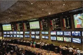  ?? NEW YORK TIMES FILE ?? Patrons place bets on sports at the MGM Grand Race &amp; Sports Book in Las Vegas in a scene that may soon be commonplac­e elsewhere. Americans are estimated to annually place $150 billion in illegal wagers on sports.