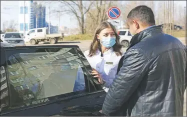  ??  ?? Kostenko opens the car door for Arzhadeyev­a as she leaves the car to visit a patient.