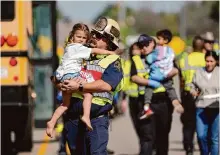  ?? Jay Janner/associated Press ?? Rescue workers carry children from Buda’s Tom Green Elementary School after their bus was involved in a fatal crash.