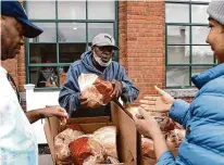  ?? ?? Mike Roberts, a cook at Open Doors’ Smilow Life Center, hands out hams during the annual Easter meal food donation event in Norwalk on Wednesday.