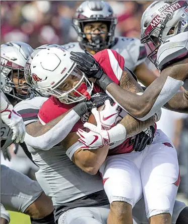  ?? NWA Democrat-Gazette/BEN GOFF ?? Arkansas running back Devwah Whaley is wrangled by Mississipp­i State’s Jamal Peters (right) and Leo Lewis during Saturday’s game at Davis Wade Stadium in Starkville, Miss. The Razorbacks fell to 2-9 for the season, matching the most losses in school history.