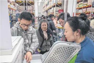  ?? ?? ABOVE
Shuen Chun-wa, centre, a shopper from Hong Kong, listens to a store employee’s sales pitch for a steam cooker at a Sam’s Club in Shenzhen.