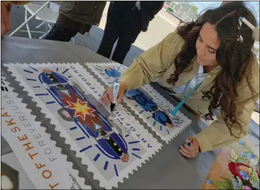  ?? (AP/U.S. Postal Service/Rod Spurgeon) ?? Greenwood autographs an “Art of the Skateboard” poster of new forever stamps Friday in Phoenix.