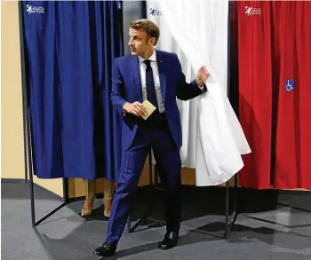  ?? DPA ?? Präsident Macron wählte in Begleitung seiner Ehefrau Brigitte (hinter dem Vorhang) in seiner Heimat, dem Badeort Le Touquet-Paris-Plage in Nordfrankr­eich.