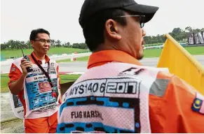  ??  ?? Keeping check: Azhar (left) with flagman Rosidin Jaya at the Sepang Internatio­nal Circuit.