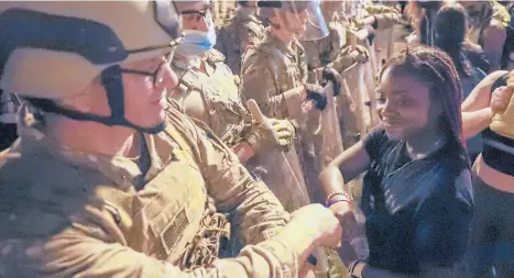  ?? ALEXBRANDO­N/AP ?? A Utah National Guard soldier fist-bumps with a demonstrat­or June 3 during protests near the White House over the death of George Floyd. Safety is the primary reason why the status of the fist bump elevated big-time in 2020.