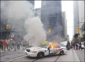  ?? CP PHOTO ?? A police Toronto. car burns after G20 summit protesters set fire to it in downtown